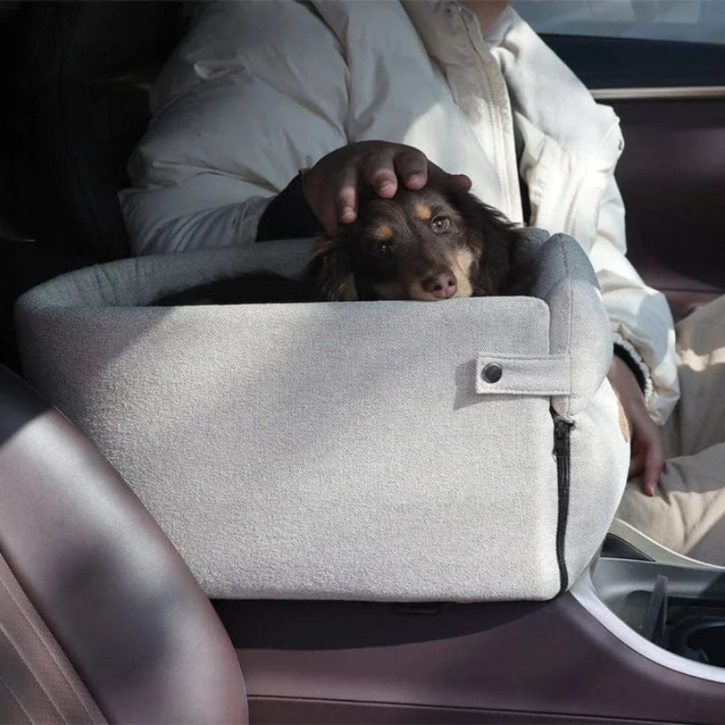 Small dog relaxing in a gray FurFree pet car seat during a car ride